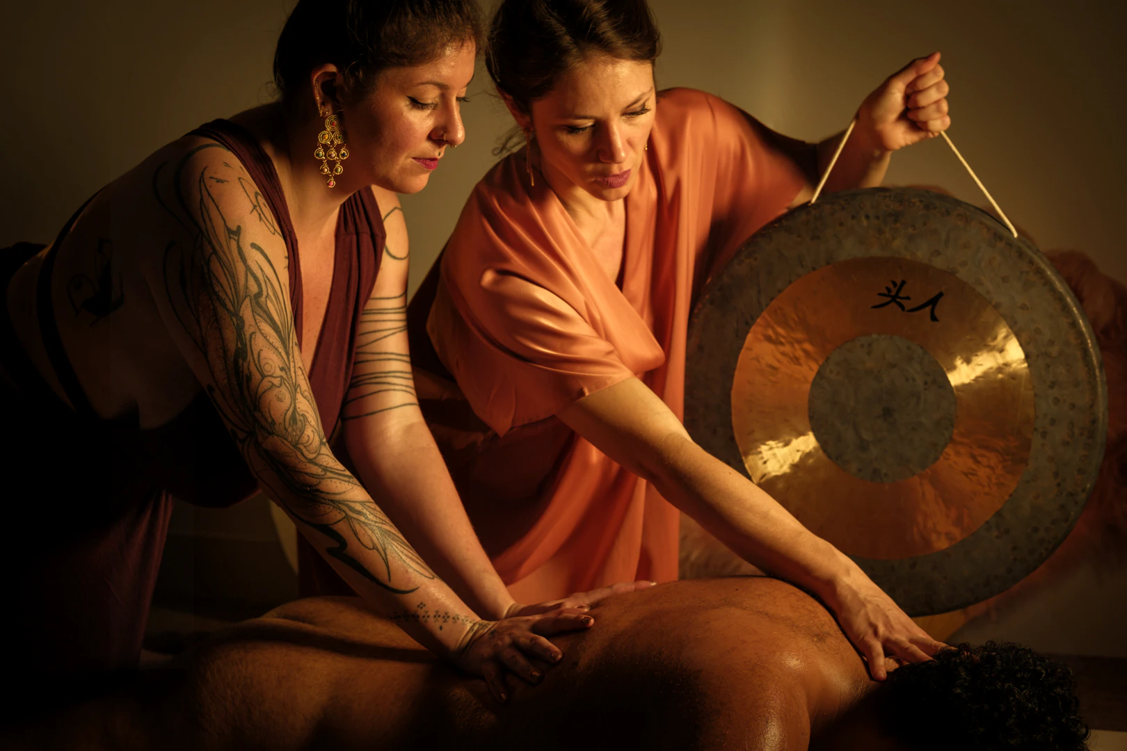Deux praticiennes et un gong pendant un massage sonore à 4 mains